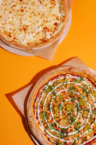 istock Delicious pizzas displayed on a vibrant orange background, showcasing cheese and unique toppings with fresh ingredients 2197929618