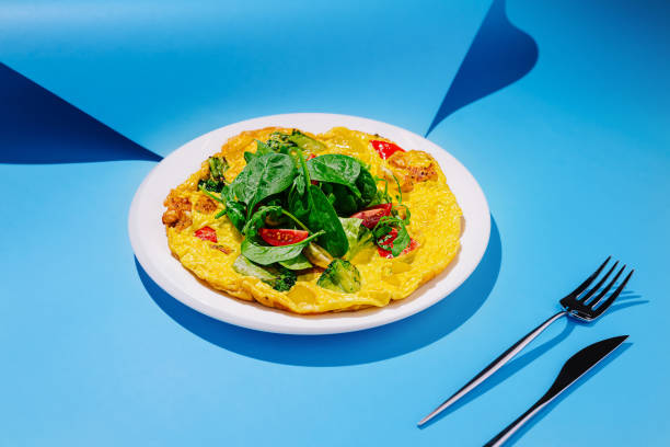 istock Delicious vegetable omelette garnished with fresh spinach on a bright blue background 2197929675