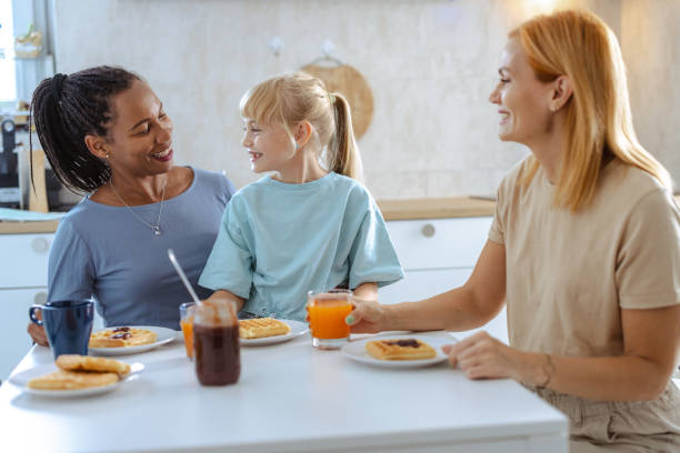 istock Two mothers enjoying breakfast with their happy child at the dining table 2197930101