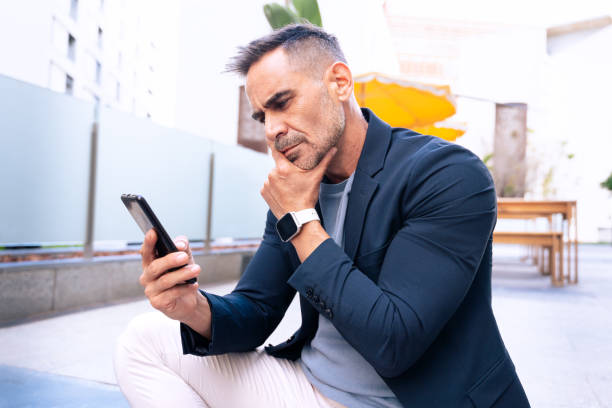 istock Thoughtful Businessman Checking Smartphone Outdoors 2197931173