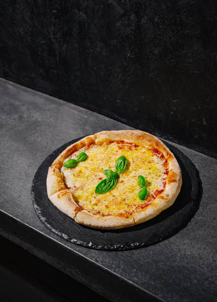 istock Freshly baked pizza with basil on a dark slate surface in a modern kitchen setting 2197931426