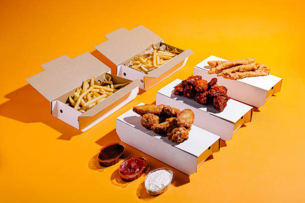 istock Fried chicken and crispy fries served in takeout boxes on vibrant orange backdrop 2197931938