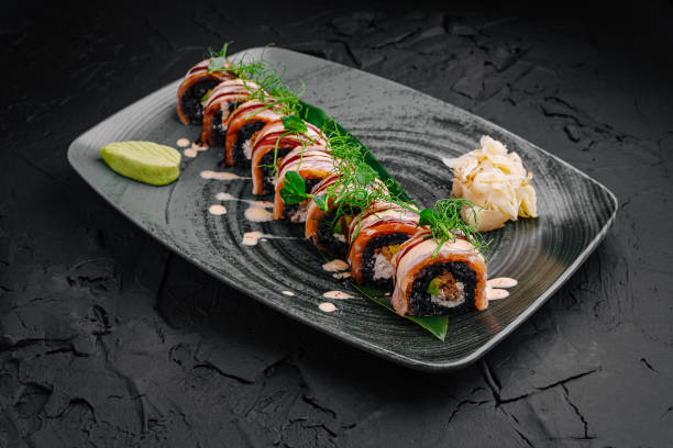 istock Exquisite sushi rolls beautifully arranged on a modern black plate with garnishes 2197933157