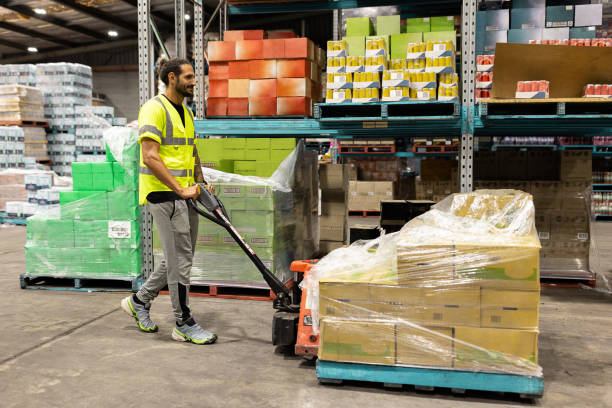 istock Worker Transporting Goods on a Pallet Jack in a Busy Warehouse 2197933421
