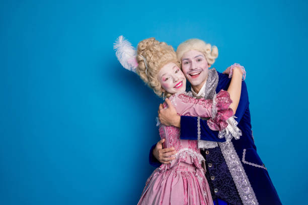 istock Charming couple embracing in elegant baroque costumes against a vibrant blue backdrop 2197934607