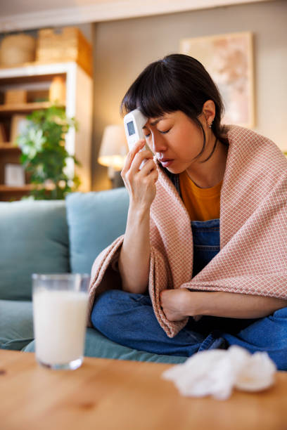 istock Sick woman having fever measuring temperature using digital contactless thermometer 2197934637