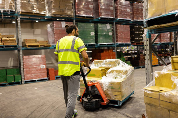 istock Worker Moving Pallet of Goods in a Large Warehouse Facility 2197936147