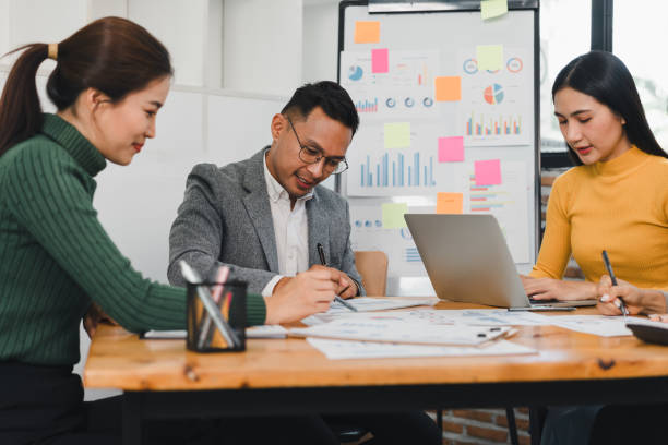 istock Collaborative business meeting with three professionals discussing data analysis and strategies. They are engaged in productive session with charts and notes around them 2197936406