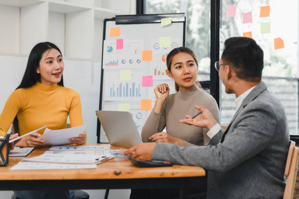 istock Collaborative business meeting with three professionals discussing strategies and analyzing data on laptop and documents. atmosphere is focused and productive 2197936407