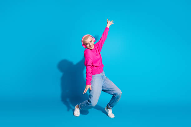 istock A young female model with a charming smile poses against a vibrant blue background, showcasing her trendy style in a pink sweater and jeans 2197936459