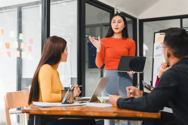 istock Young woman presenting ideas to colleagues in modern office 2197936534