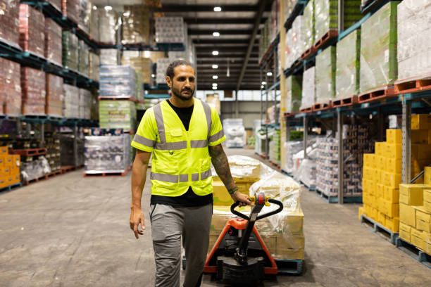 istock Warehouse Worker Transporting Goods Using Manual Pallet Jack in Distribution Center 2197936760