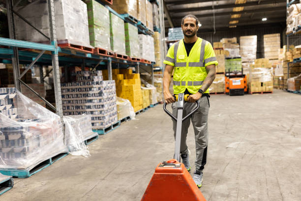 istock Man Operating Pallet Jack in a Large Warehouse Environment 2197937115