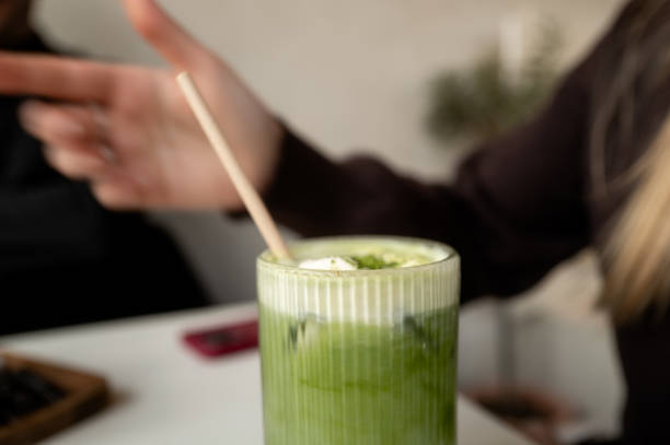 Hand gesturing near iced matcha latte drink