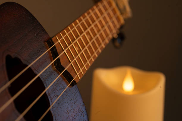 istock lighted candle illuminates a ukulele with warm light 2197939540