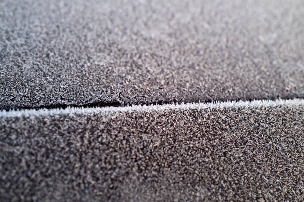 Detailed view of frost forming intricate patterns on a textured surface, highlighting the beauty of winter