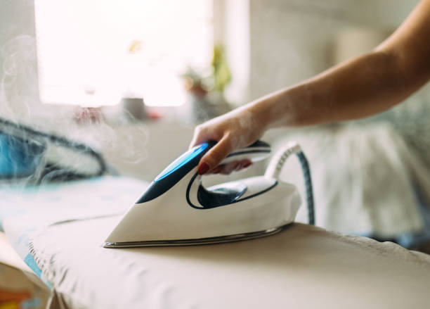 istock Ironing Clothes with Moden Steam Iron in Bright Daylight at Home 2197940068