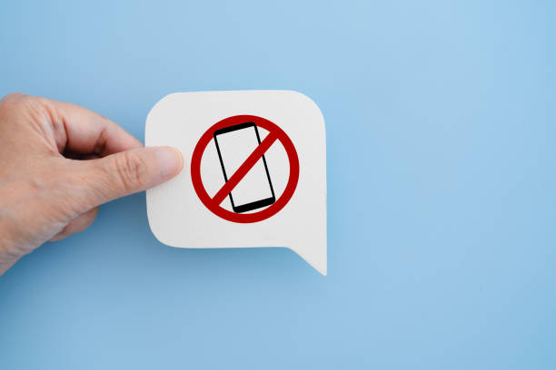 istock hand hold No mobile phone sign on real white speech bubble paper cut on blue background 2197941025