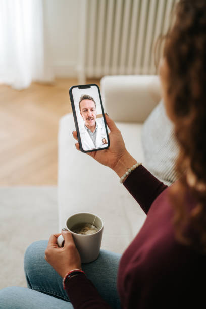 istock Woman using phone talk to doctor sitting on sofa 2197941827