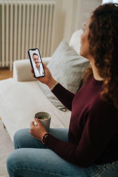 istock Woman using phone talk to doctor sitting on sofa 2197941831
