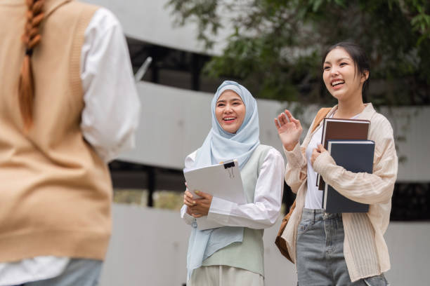 istock Diverse female students greeting a friend, sharing joy and study materials. 2197941956
