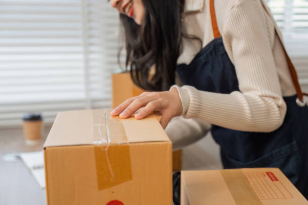 istock Diverse young woman sealing cardboard boxes in a retail workspace. 2197942567