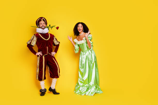 istock Two costumed individuals posing cheerfully against a bright yellow backdrop, dressed in elegant historic attire 2197942791