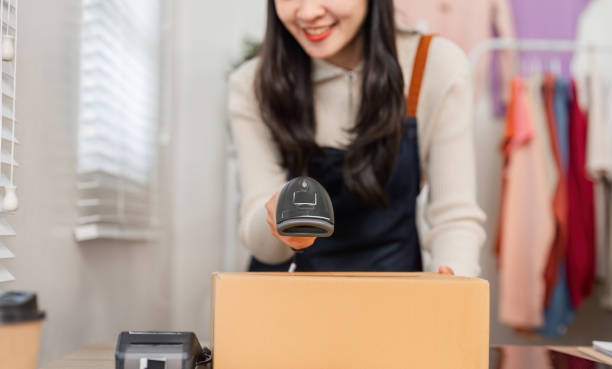 istock Diverse young woman scanning a cardboard box with a barcode scanner in retail. 2197942827