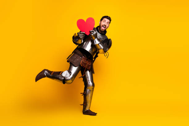 istock Happy knight in shining armor holding a heart on a bright yellow background 2197943432
