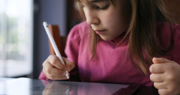 istock Child girl watching online tutorial on laptop computer and drawing digital pictures using digitized pen and digital tablet 2197943495