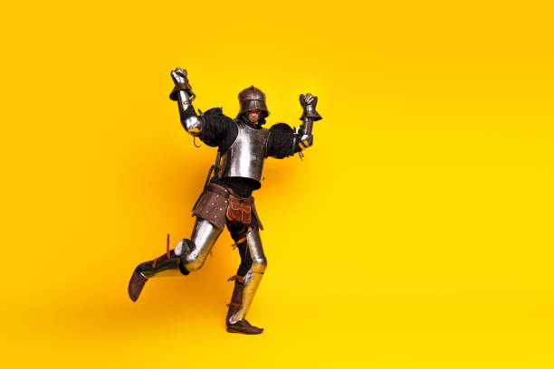 istock Energetic knight in medieval armor jumping against a vibrant yellow backdrop 2197943541