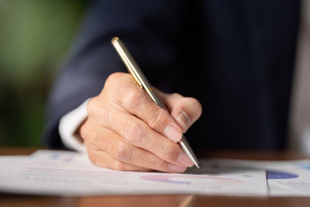 istock Elderly businessman signing documents in office setting professional environment close-up view for success 2197943606