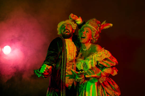 Two individuals in detailed costumes dance under vibrant lighting, evoking historical elegance, while expressing celebratory joy in a festive atmosphere.