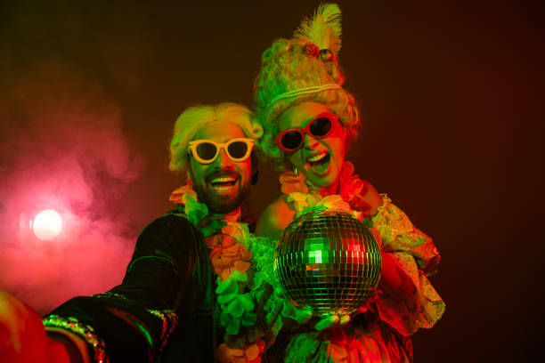istock Two costumed individuals enjoying a vibrant masquerade disco scene under bright colored lights 2197943683