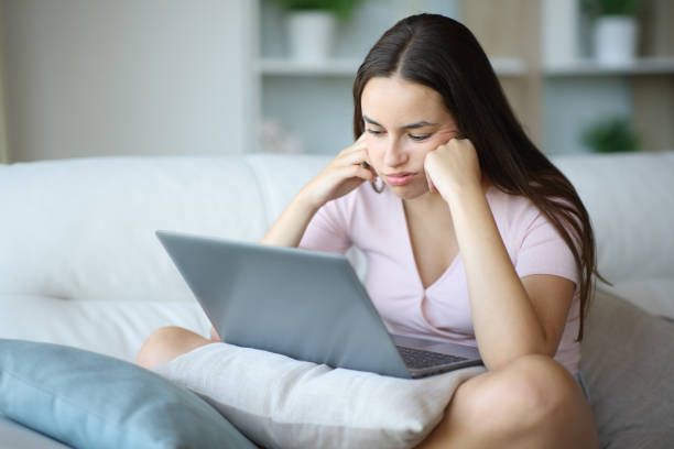 istock Bored woman using laptop on a couch at home 2197946115