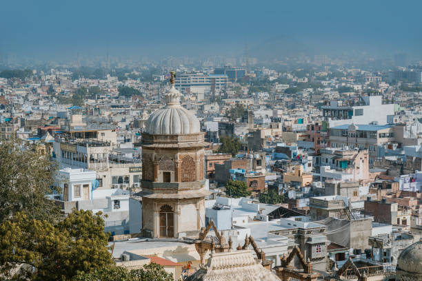 A panoramic view of Udaipur's cityscape with historic domed structures amidst an urban landscape, vibrant buildings, dense layout, and clear skies creating a serene horizon.