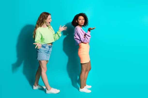 istock Two young women gesturing expressively against a turquoise background, showcasing diverse styles and trends in casual fashion. 2197947803