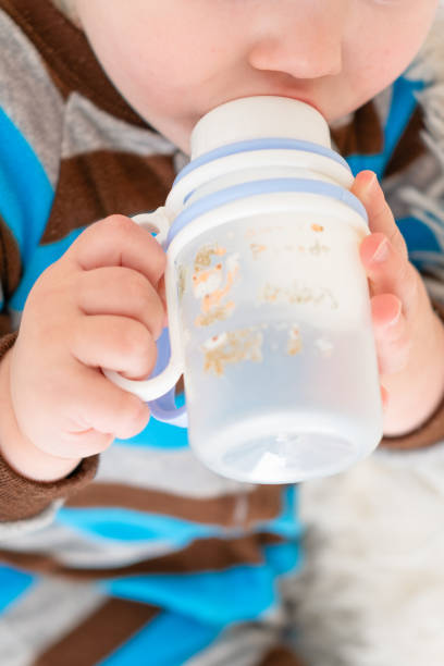 istock little boy sitting on the sofa drinking milk from a bottle 2197951185
