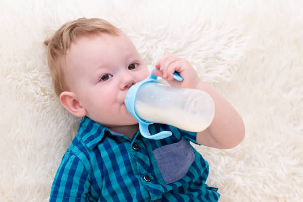 istock little boy sitting on the sofa drinking milk from a bottle 2197951204