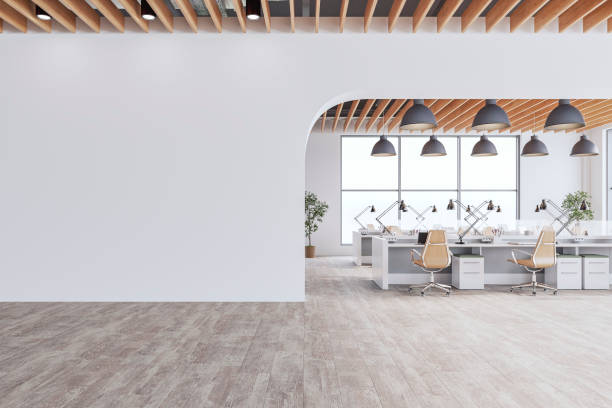 istock Semi-empty office interior with arched white blank wall and copy space,  a wooden slats ceiling, work desks and large windows, on wood look tiled floor 2197954733