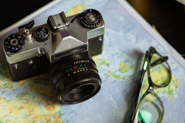 Travel planning. Vintage film camera and world map on rustic black table.