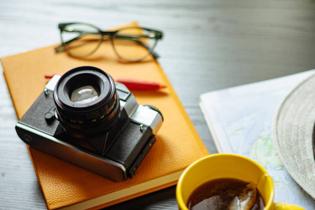 Travel planning. Vintage film camera, world map and straw hat on rustic black table.