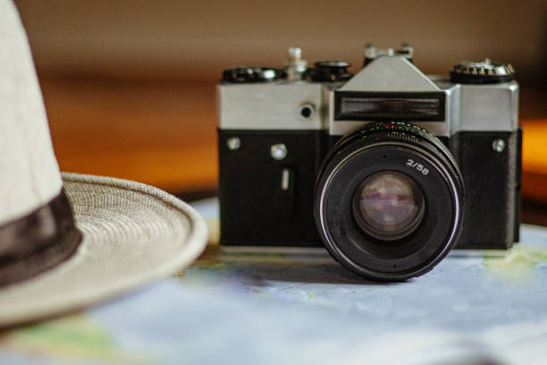 Travel planning. Vintage film camera, world map and straw hat on rustic black table.