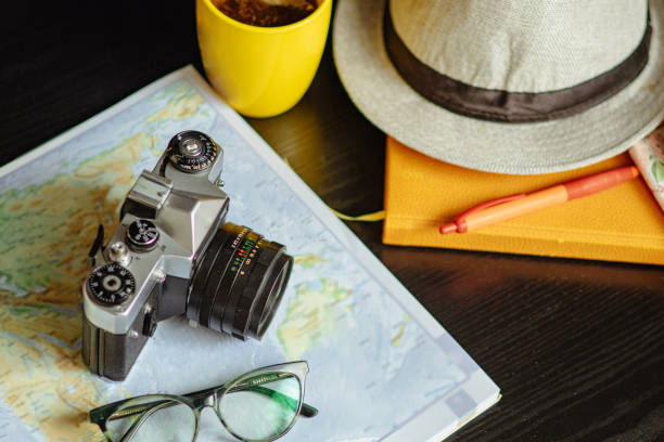 istock Travel planning. Vintage film camera, world map and straw hat on rustic black table. 2197955640