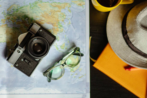 istock Travel planning. Vintage film camera, world map and straw hat on rustic black table. 2197956144
