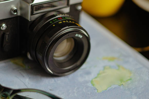 Travel planning. Vintage film camera and world map on rustic black table.