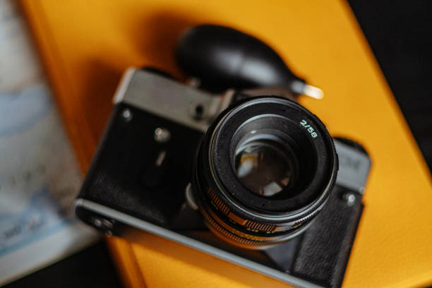 Travel planning. Vintage film camera, world map and straw hat on rustic black table.