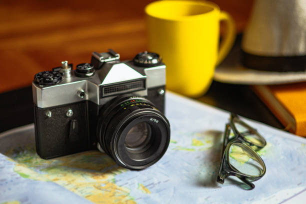 Travel planning. Vintage film camera and world map on rustic black table.
