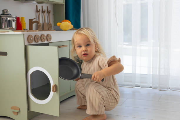 istock Child plays with kitchen toys while holding an apple in a bright, modern indoor play space 2197961933