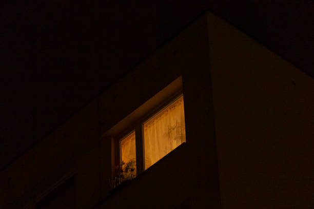 istock A Dimly Lit Window at Night Surrounded by an Urban Background Scene 2197963332